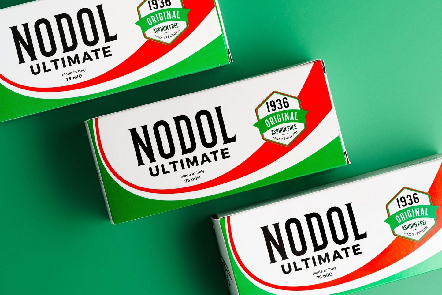 Three boxes of Nodol Aspirin-Free Pain Cream by 1936 Original rest on a green surface, highlighting its natural formula for effective relief of muscle pain.